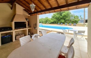 Un patio al aire libre con una mesa y sillas, una parrilla y vistas a una piscina.
