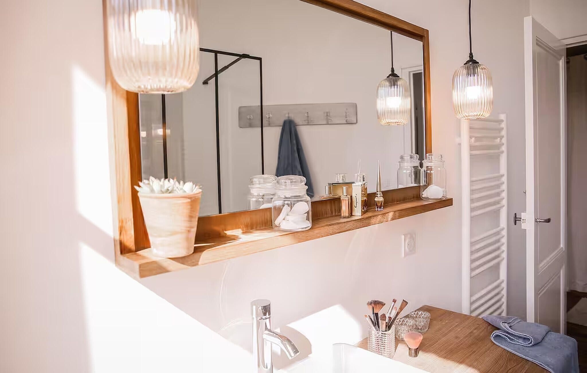 A bathroom with a large mirror, a wooden vanity, a sink, and a towel rack.