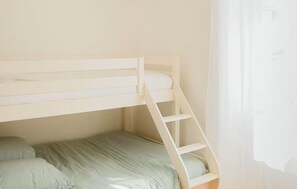 A bunk bed with a ladder, a single bed below, and a window with curtains. - Superbe maison en pierre (Sauternes)