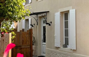 A building with a wooden fence, a door, and two windows with shutters. - Superbe maison en pierre (Sauternes)