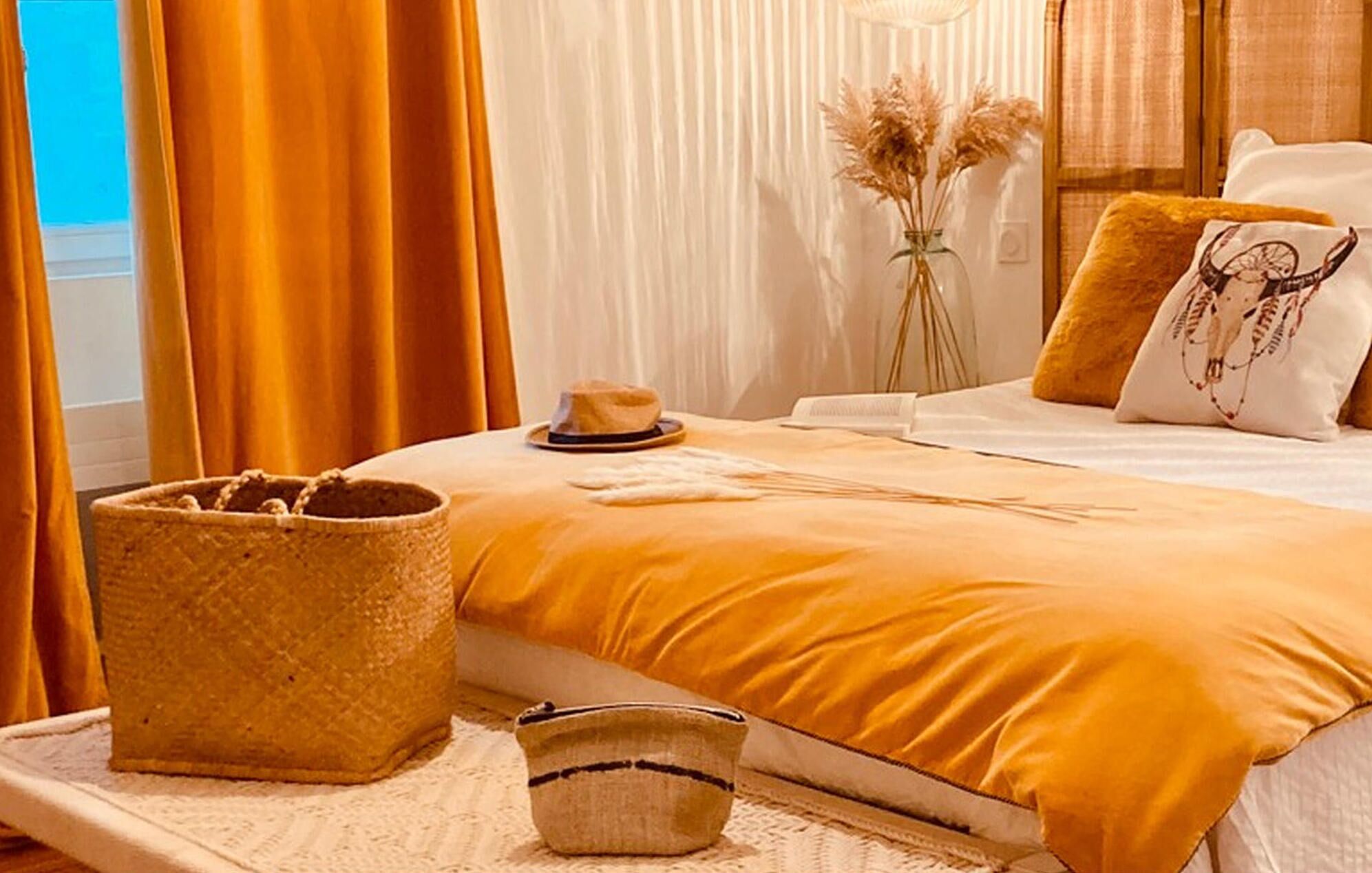 A bed with a yellow bedspread, a woven basket, and a small bowl on a white textured surface.