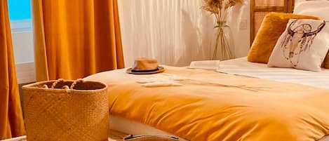A bed with a yellow bedspread, a woven basket, and a small bowl on a white textured surface.