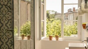 Ein Badezimmer mit Fenster, Topfpflanzen und einem Waschbecken.