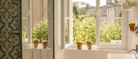 A bathroom with a window, potted plants, and a sink.
