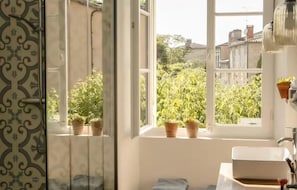 Ein Badezimmer mit Fenster, Topfpflanzen und einem Waschbecken.