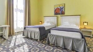 A hotel room with two beds, a patterned carpet, a painting on the wall, and a window with curtains. - Sighisoara Hotel (Sighisoara)