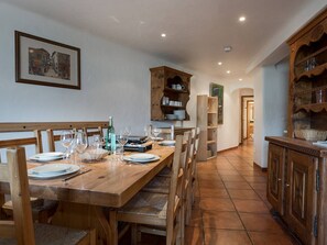 Ein Essbereich mit Holztisch und -stühlen, eine Küche mit Holzausstattung und ein gerahmtes Bild an der Wand.