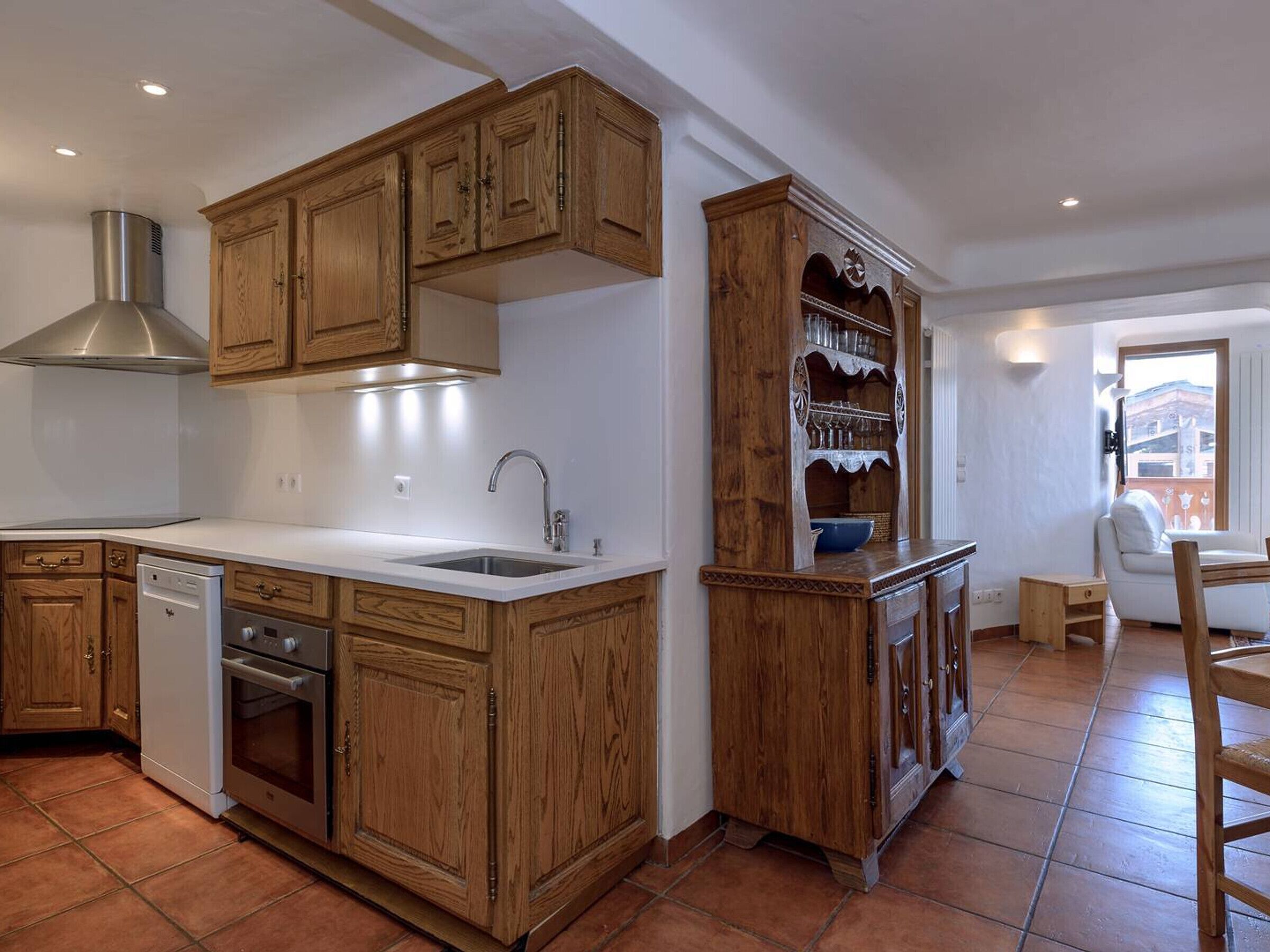 A kitchen with wooden cabinets, a stainless steel range hood, a dishwasher, and a sink.