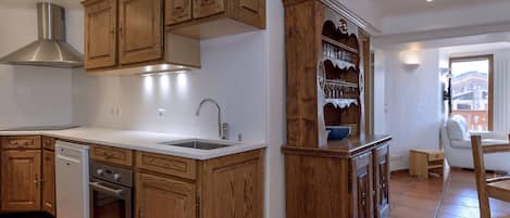 Una cocina con gabinetes de madera, un extractor de acero inoxidable, lavavajillas y un fregadero.