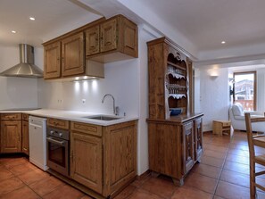 Eine Küche mit Holzschränken, einer Edelstahl-Dunstabzugshaube, einem Geschirrspüler und einem Spülbecken.