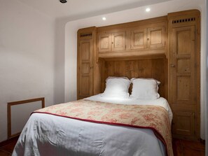Ein Schlafzimmer mit einem Bett, einem Holzschrank und einem kleinen Tisch.