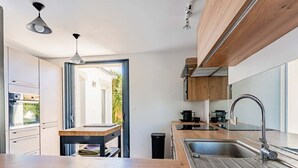 Una cocina moderna con encimera de madera, pileta de acero inoxidable y electrodomésticos integrados.