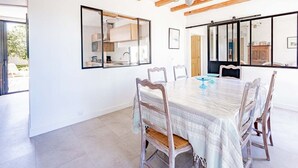 Un comedor amplio con una gran mesa, sillas de madera y una araña.