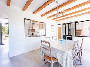 A spacious dining area with a large table, wooden chairs, and a chandelier. - Elegant house in nature - 6 guests (Saint-Clément-des-Baleines)