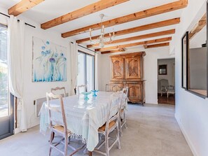 Ein Essbereich mit Holzbalkendecke, einem Kronleuchter, einem für sechs Personen gedeckten Tisch und einem großen Gemälde an der Wand.