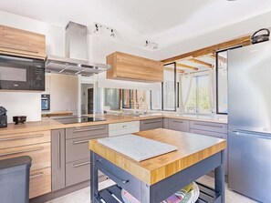 A modern kitchen with a central island, stainless steel appliances, and wooden cabinetry. - Elegant house in nature - 6 guests (Saint-Clément-des-Baleines)