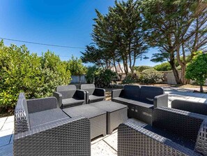Eine Terrasse mit Korbmöbeln und Blick auf Bäume sowie ein Gebäude im Hintergrund.