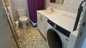 A compact bathroom with a toilet, a sink, and a washing machine. - Cross apartment with parking - 4 guests (Canet-en-Roussillon)
