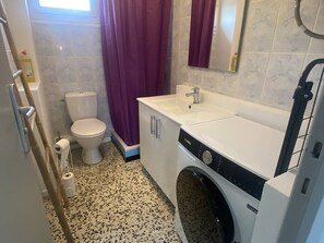Ein kleines Badezimmer mit Toilette, Waschbecken und Waschmaschine.
