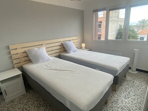 Ein Schlafzimmer mit zwei Betten, einem Nachttisch, einem Fenster mit Blick und einer Heizung.