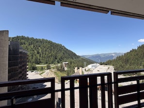 A view from a balcony overlooking a mountainous landscape with buildings and a road. - Renovated apartment, ideal location - 6 guests (Plagne Bellecôte)