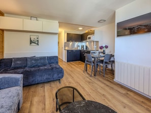 A modern living space with a sofa, dining table, chairs, and a kitchen area. - Renovated apartment, ideal location - 6 guests (Plagne Bellecôte)