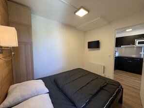 A bedroom with a bed, a wooden wardrobe, a television, and a kitchenette in the adjacent room. - Renovated apartment, ideal location - 6 guests (Plagne Bellecôte)