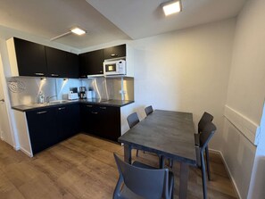 A modern kitchen with dark cabinets, a microwave, and a dining table with chairs. - Renovated apartment, ideal location - 6 guests (Plagne Bellecôte)