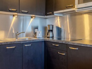 Una cucina moderna con elettrodomestici in acciaio inossidabile, una macchina per il caffè e un lavello.