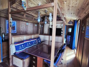 Ein Holzinnenraum mit einem Glastisch, Holzbänken und einer Decke mit freiliegenden Balken.