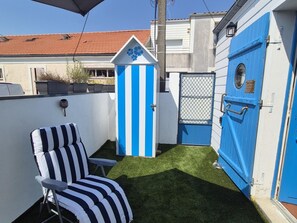 A small outdoor area with a striped chair, a blue door, and a white building with a red roof. - Unique house in the heart of Fouras - 2 guests (Fouras)