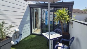 A small patio area with a table and chairs, a potted plant, and a sliding glass door. - Unique house in the heart of Fouras - 2 guests (Fouras)