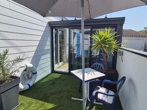 Ein kleiner Patio-Bereich mit Tisch und Stühlen, einem Blumentopf und einer Terrassentür.