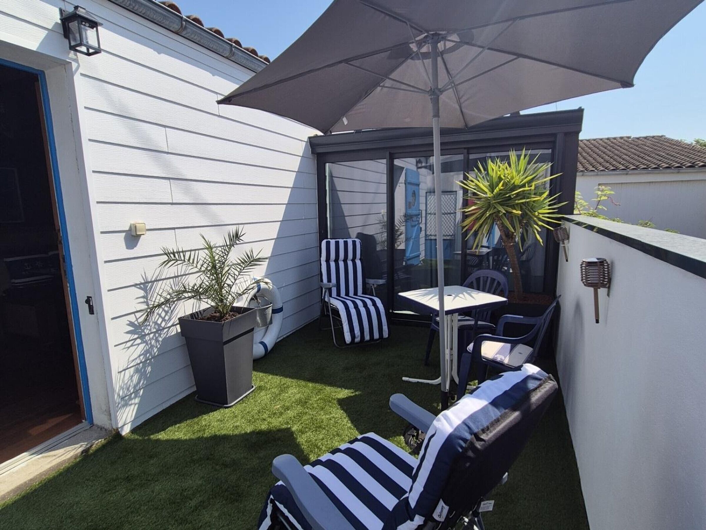 Eine Terrasse mit Tisch, Stühlen und einem Blumentopf.