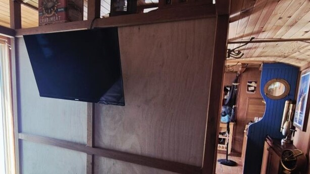 A room with a bed, a television mounted on a wooden partition, and a small desk with a chair. - Unique house in the heart of Fouras - 2 guests (Fouras)