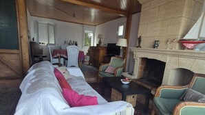 Een gezellige woonkamer met een open haard, comfortabele zitmogelijkheden en een televisie.