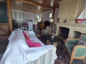 A cozy living room with a fireplace, comfortable seating, and a television. - Charming house, sea view - 4 guests (Fouras)