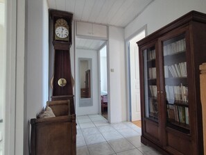 A hallway with a wooden bench, a tall grandfather clock, a mirror, and a bookcase. - Charming house, sea view - 4 guests (Fouras)