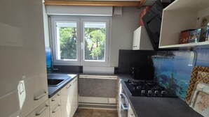 Een kleine keuken met raam, fornuis en magnetron.