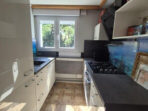 A compact kitchen with a window, a stove, and a microwave. - Charming house, sea view - 4 guests (Fouras)