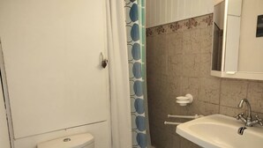 Une salle de bain avec des toilettes, un lavabo, un rideau de douche et un mur carrelé.
