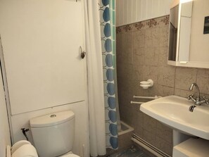 Ein Badezimmer mit Toilette, Waschbecken, einer Duschkabine und einer gefliesten Wand.