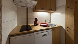 A compact kitchen with a dishwasher, a red kettle, and a sink. - Apartment with station view - 2 guests (Valmorel)