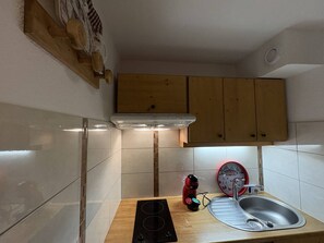 A compact kitchen with a built-in stove, a sink, and wooden cabinets. - Apartment with station view - 2 guests (Valmorel)