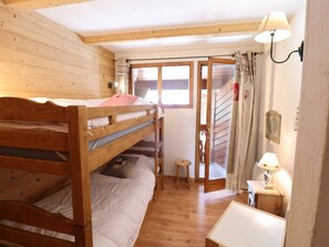 Ein Zimmer mit einem hölzernen Etagenbett, einem kleinen Hocker und einem Tisch.