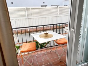 A balcony with a white table, orange cushions, and a woven placemat. - Apartment with AC & WiFi - 3 guests near beach (Platja d'Aro)