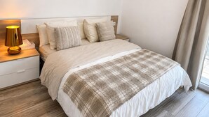 A neatly made bed with a plaid blanket, a bedside lamp, and a wooden nightstand. - Apartment with AC & WiFi - 3 guests near beach (Platja d'Aro)