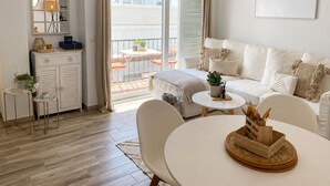 A modern living room with a sofa, a dining table, and a balcony with a table and chairs. - Apartment with AC & WiFi - 3 guests near beach (Platja d'Aro)