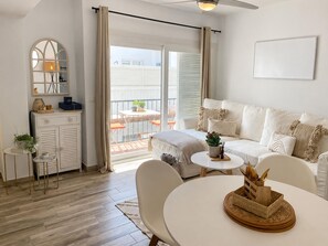 A modern living room with a sofa, a dining table, and a balcony with a table and chairs. - Apartment with AC & WiFi - 3 guests near beach (Platja d'Aro)
