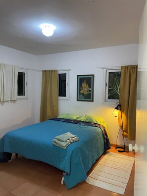 A bedroom with a bed, a window, a painting, and a lamp. - Charming 1-bedroom apartment in Playa Juan Dolio near the beach (Playa Juan Dolio)